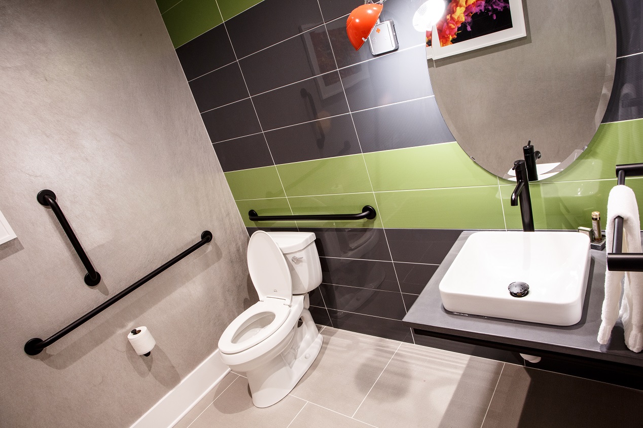 Penthouse suite bathroom showing toilet and sink with green and gray tiling